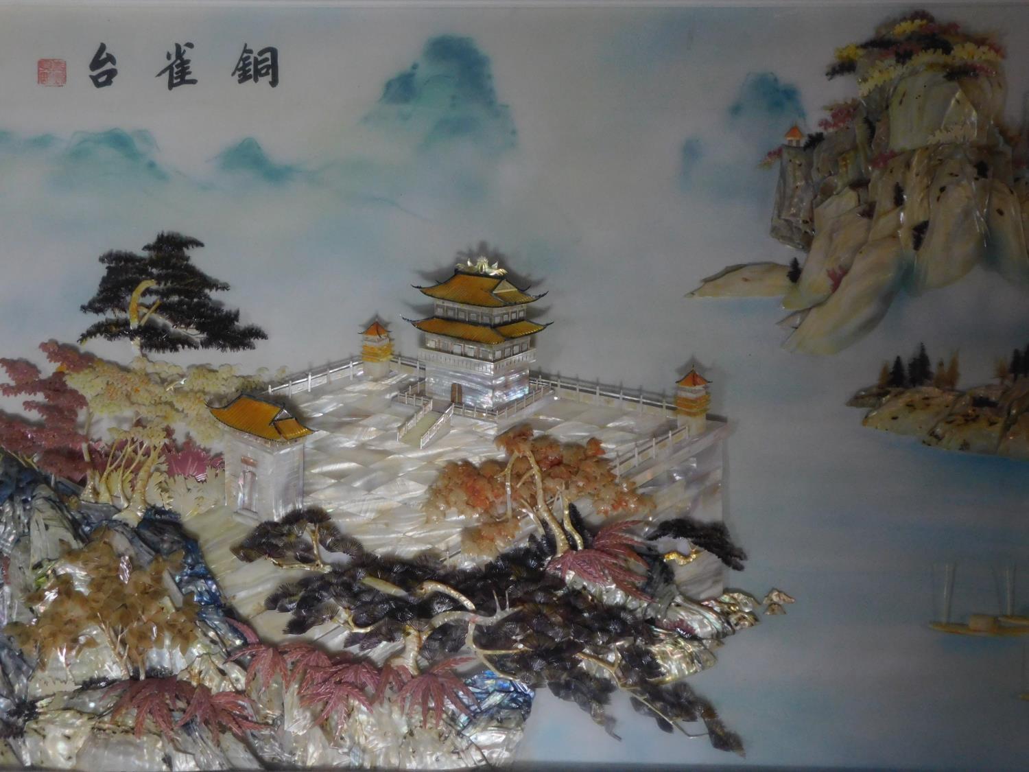 A large framed and glazed Chinese abalone shell and mother of pearl relief artwork depicting a