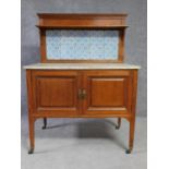 An Edwardian mahogany washstand with tiled back superstructure above marble top on panel doors on