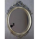 A silvered wall mirror with bevelled glass set within a decorative floral scroll frame. 94x66cm