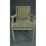 A Louis XVl style painted white armchair in striped upholstery and raised on tapering fluted