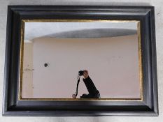 An ebonised and gilt rectangular wall mirror. 84x114cm