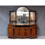 A Victorian style carved flame mahogany sideboard with arched triple section mirrored back.
