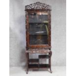 A late 19th century Chinese rosewood display cabinet with scrolling bamboo carved pediment above