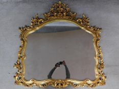 An antique style gilt framed wall mirror with floral surmount and decoration. 116x113cm
