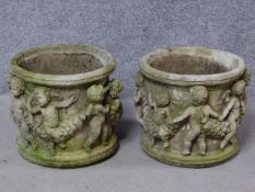 A pair of cylindrical concrete garden jardinieres with dancing cherub and leaf garland relief