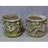 A pair of cylindrical concrete garden jardinieres with dancing cherub and leaf garland relief