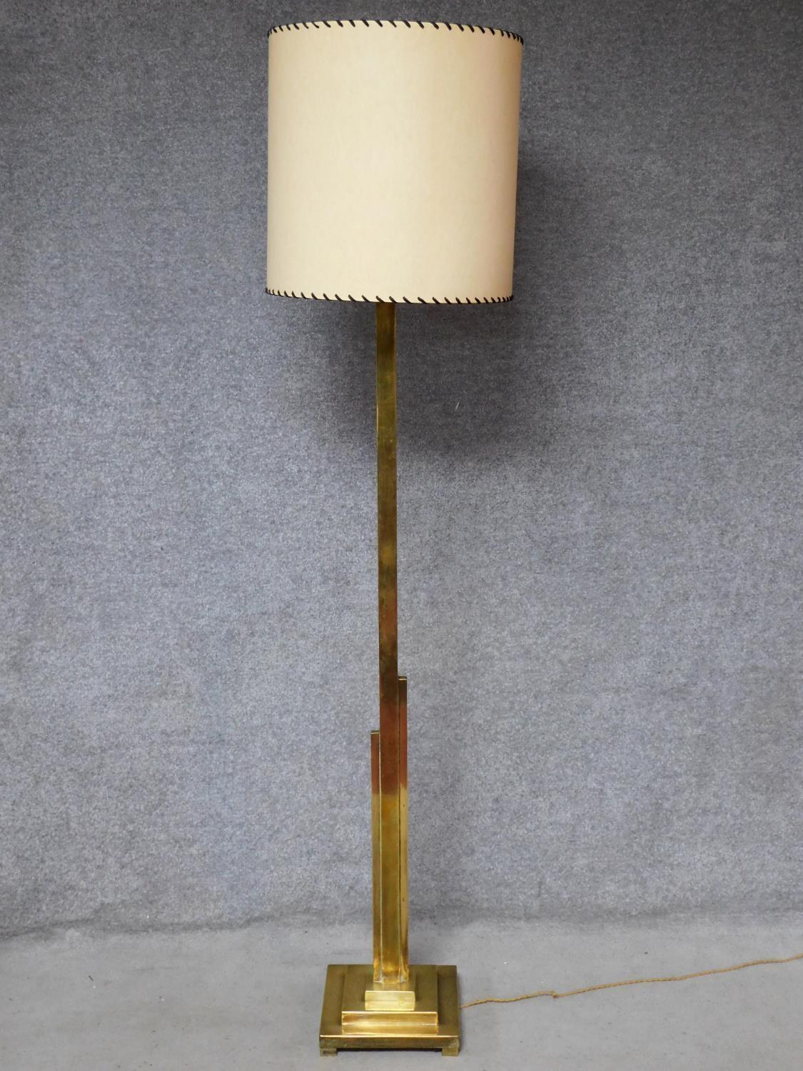 An Art Deco brass standard lamp of geometric outline and square stepped base resting on four block