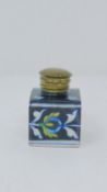 An antique glazed ceramic perfume bottle with brass lid, decorated with a stylized floral and