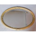 An oval gilt framed wall mirror with reeded and ribbon decoration fitted with bevelled plate.