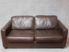 A dark tan leather upholstered two seater sofa bed. H.70 W.180 D.100cm (sofa)