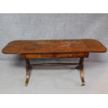 A late 19th century mahogany Regency style sofa table on swept supports terminating in reeded