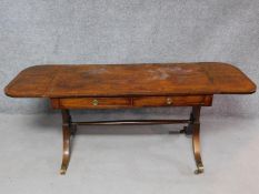 A late 19th century mahogany Regency style sofa table on swept supports terminating in reeded