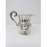 A Georgian dragooned silver cream jug with floral and foliate design handle. Gilded interior with