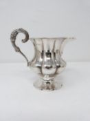 A Georgian dragooned silver cream jug with floral and foliate design handle. Gilded interior with