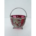 An antique silver plated sugar bowl with cranberry glass liner. Basket is pierced with a butterfly