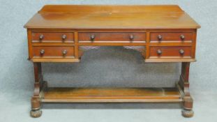 A William IV mahogany writing table with an arrangement of five drawers on reeded bun feet united by