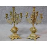 A pair of brass five branch table candelabra with scrolling foliate decoration on quadruped platform
