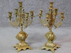 A pair of brass five branch table candelabra with scrolling foliate decoration on quadruped platform