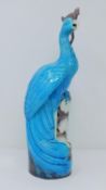An antique Chinese turquoise glazed peacock perched on a pierced glazed aubergine base with white