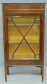 An Edwardian mahogany display cabinet with astragal glazed door enclosing display shelves on