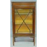 An Edwardian mahogany display cabinet with astragal glazed door enclosing display shelves on