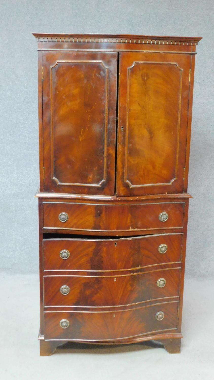 A Georgian style flame mahogany tallboy with panel doors enclosing shelves above drawer and panel