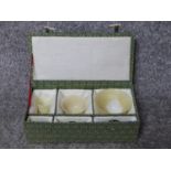 A fabric covered boxed collection of three graduating Chinese Jade libation cups with wooden stands.