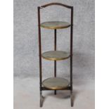 A late 19th century mahogany three tier folding cake stand fitted with embossed brass trays. maker's