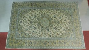 A Tabriz style rug with central double pendant medallion surrounded by repeating floral motifs on an