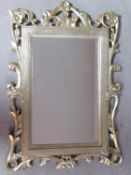 A bevelled glass wall mirror in decorative silvered and foliate frame. 95x66cm