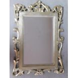 A bevelled glass wall mirror in decorative silvered and foliate frame. 95x66cm