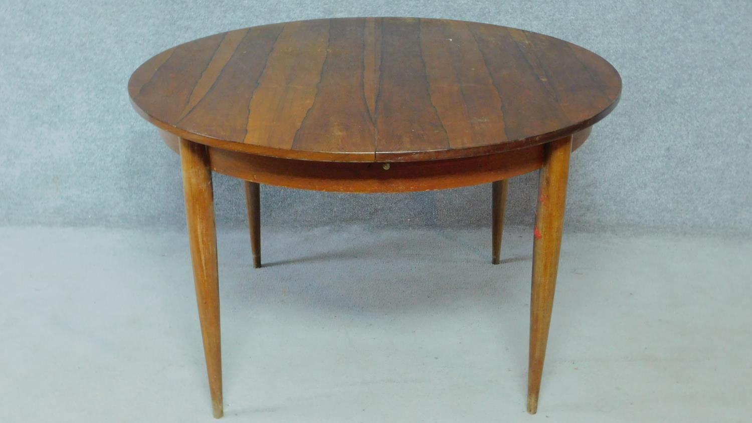 A vintage rosewood extending dining table on circular tapering supports fitted with swivelling - Image 4 of 4