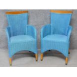 A pair of Lloyd Loom conservatory armchairs on circular teak brass capped supports. H.93cm