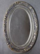 A floral and silvered frame wall mirror with oval bevelled plate. 91x63cm
