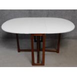 A vintage drop flap dining table with white painted drop flap top on teak gateleg action base. H.