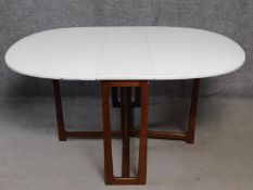 A vintage drop flap dining table with white painted drop flap top on teak gateleg action base. H.