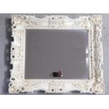 A white lacquered floral scrolling framed wall mirror fitted with bevelled plate. 68x58cm