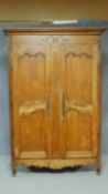 An antique French country carved chestnut armoire with panel doors enclosing shelves on cabriole