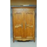 An antique French country carved chestnut armoire with panel doors enclosing shelves on cabriole