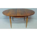 A vintage rosewood extending dining table on circular tapering supports fitted with swivelling