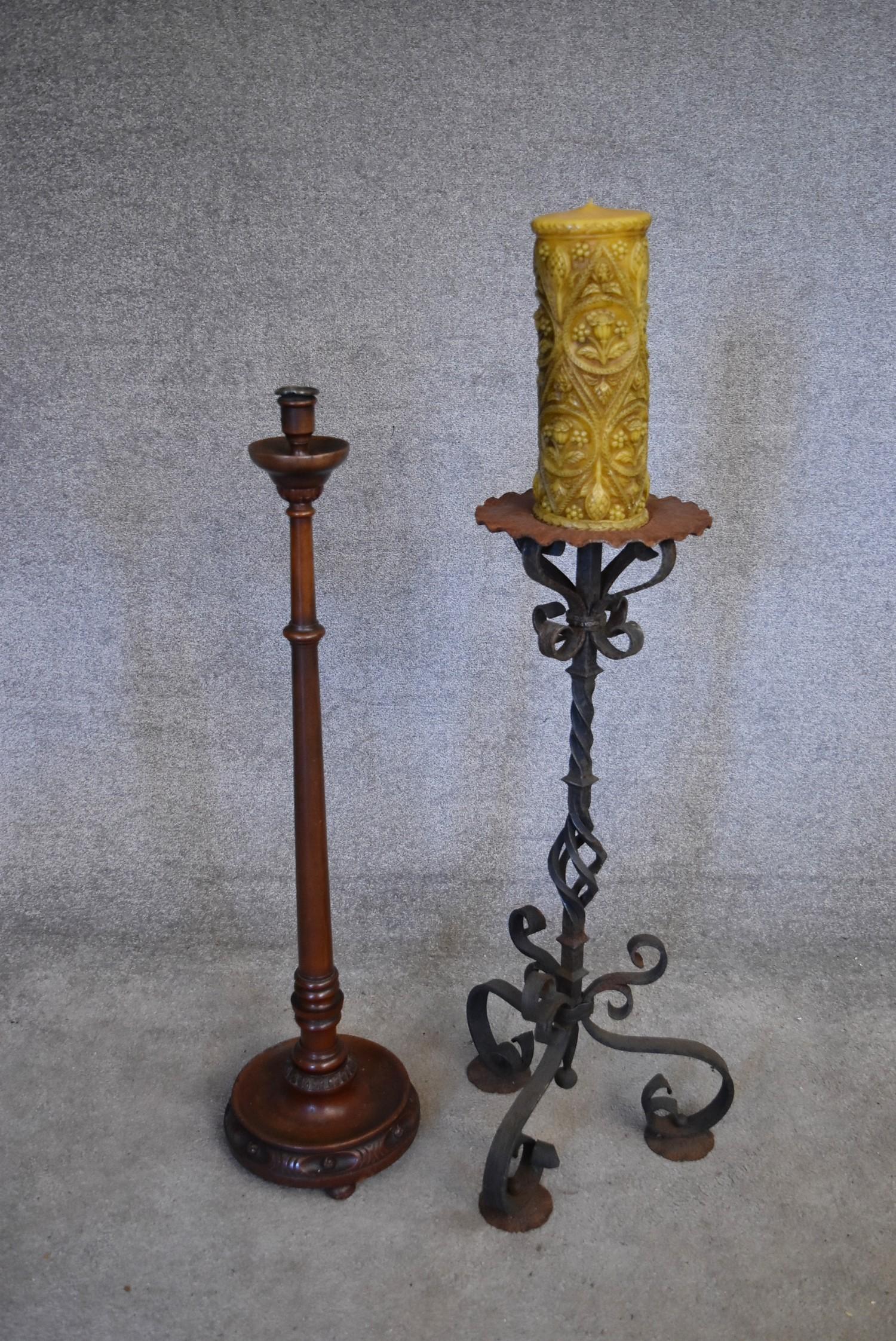 A wrought iron floor standing pricket candlestick and a turned wooden example. H.100cm