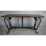 A rectangular console table with planked cleated hardwood top on metal cabriole scrolling