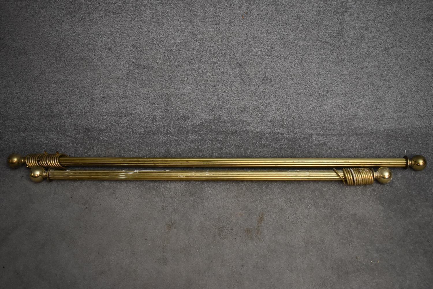 Two brass fluted curtain poles and rings with spherical finials. Longest L.165/Shortest L.138cm