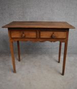 An antique country elm two drawer side table with shaped frieze on square section supports. H.