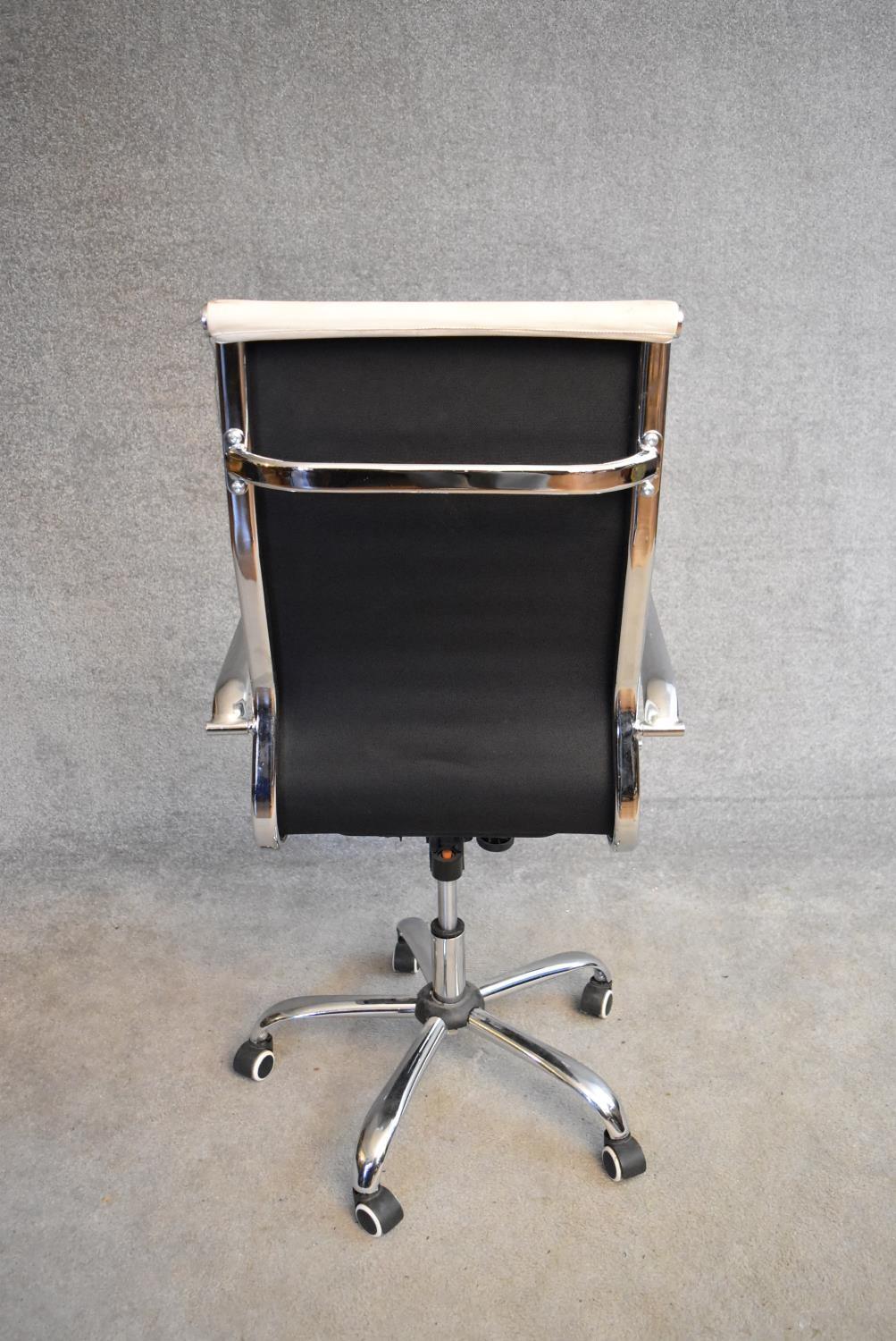A Charles Eames style swivel office armchair in cream vinyl upholstery. H.114x50cm - Image 3 of 4