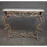 A mid 20th century white painted wrought iron console table with shaped marble top on scrolling