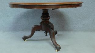 A Victorian mahogany circular dining table with tilt top action raised on carved tripod supports.