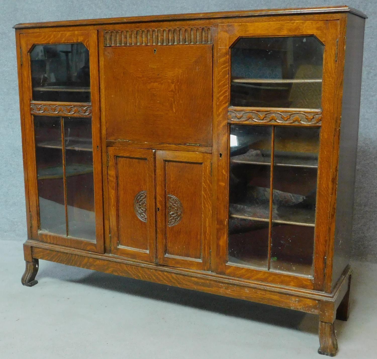 A mid 20th century carved oak bureau bookcase with central fitted secretaire section flanked by