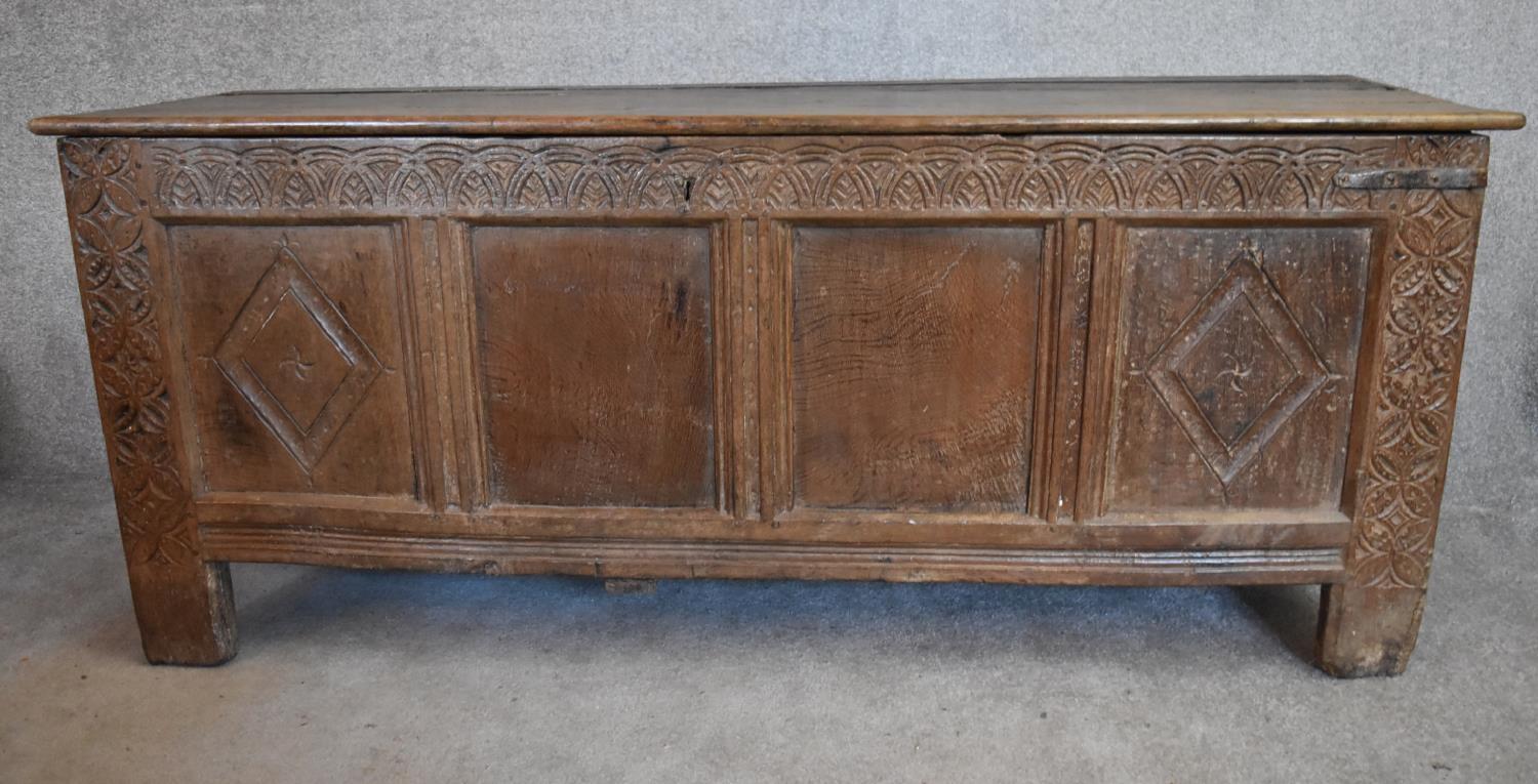 A 17th century carved oak coffer with hinged lidded top and panelled sides with lozenge decoration