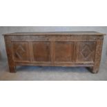 A 17th century carved oak coffer with hinged lidded top and panelled sides with lozenge decoration